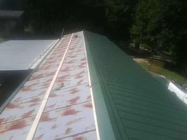 Old rusted panels beside newly installed green metal roofing — Wind Damage Roof Repair by Roofing Brothers in Ravenna
